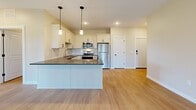 This thoughtfully designed 2-bedroom, 2-bathroom residence in Monticello, MN offers a comfortable and functional single-floor layout. The open-concept kitchen and living area serves as the heart of the home, featuring light hardwood-style flooring, recessed lighting, and a seamless flow between spaces. The kitchen is outfitted with crisp white shaker cabinets, dark countertops, a subway tile backsplash, a central island with pendant lighting, and a full suite of stainless steel appliances including a refrigerator, range, microwave, and dishwasher. The living area extends toward a sliding glass door dressed with vertical blinds, allowing for natural light and outdoor access. The spacious primary bedroom is carpeted and features a large window with open views of the surrounding landscape. The second bedroom also offers generous proportions with hardwood-style flooring, a sliding glass door, and ample natural light. Both bathrooms are finished with white vanities, tile-style flooring, and brushed nickel fixtures — one featuring a tub-shower combo and the other a walk-in shower. A dedicated in-unit laundry room houses a full-size side-by-side washer and dryer with built-in shelving for added storage convenience.