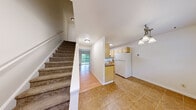 Located at 210 Vineyard Ave in Highland, NY, this two-story home offers a functional and well-organized layout spread across two floors. The main level features a combined kitchen and living area, with warm wood-look flooring flowing through the living space and tile flooring in the kitchen. The kitchen is equipped with light maple cabinetry, granite-look countertops, a full suite of white appliances, and a skylight that fills the space with natural light. A half-wall peninsula connects the kitchen to the living area, which opens through a sliding glass door to a private deck overlooking a lush, wooded backdrop — a standout feature of the home. A carpeted staircase with white railings leads to the upper level, where two bedrooms are situated. Both bedrooms feature plush carpeting and neutral wall tones. The primary bedroom includes a ceiling fan with a light fixture, adding comfort and functionality. The second bedroom is served by baseboard heating. The full bathroom is finished with warm beige tile, a tub/shower combination, a vanity with storage, and mosaic tile flooring. A hallway connects the upper-level rooms efficiently, completing this neatly arranged two-floor home.
