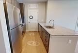This 950-square-foot, single-floor apartment at 80 Lawrenceville Suwanee Rd, Unit 1503 in Lawrenceville, GA offers 2 bedrooms and 3 bathrooms with a clean, modern aesthetic throughout. The open-concept kitchen and living area serves as the heart of the home, featuring light wood-style flooring, recessed lighting, and a central island with granite countertops. The kitchen is equipped with stainless steel appliances, dark wood cabinetry, and ample counter space, flowing seamlessly into the living area, which includes a ceiling fan and access to an exterior door with natural light from large windows. Both bedrooms are carpeted and feature ceiling fans, neutral toned walls, and generous windows with outdoor views. The 160-square-foot primary bedroom includes its own closet and direct access to a private bathroom. The bathrooms are finished with granite-topped wood vanities and light wood-style flooring. One bathroom features a walk-in glass shower, while another offers a soaking tub and shower combo with tile surround. Two closets provide practical storage throughout the unit. The consistent neutral color palette and modern finishes create a cohesive and comfortable living environment.