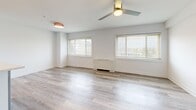 This 2-bedroom, 1-bathroom residence in Towson, Maryland offers a well-designed single-floor layout that maximizes both functionality and comfort. The open-concept living, dining, and kitchen area serves as the heart of the home, featuring light gray luxury vinyl plank flooring that flows seamlessly throughout the main living spaces. The kitchen is outfitted with stainless steel appliances including a gas range, over-the-range microwave, and refrigerator, complemented by white shaker-style upper cabinets, gray lower cabinets, quartz countertops, a subway tile backsplash, and a peninsula that provides additional workspace and separation from the living area. An in-unit washer is also integrated into the kitchen space. The living room benefits from multiple windows with blinds, allowing for ample natural light, and is fitted with a ceiling fan. Both bedrooms feature plush carpeting, ceiling fans with integrated lighting, and generous closet space, with the primary bedroom offering a notably spacious layout. The bathroom includes a full tub-shower combination with white tile surround, contrasting dark accent tile, and brushed gold fixtures. Three closets throughout the unit provide substantial storage. The overall aesthetic is clean, bright, and modern.