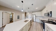 This two-story residence in Metuchen, NJ offers a well-designed layout across two floors, totaling over 1,300 square feet of living space. The main floor is anchored by an open-concept kitchen and living area, where a large central island with a quartz countertop and undermount sink serves as the focal point. Pendant lighting illuminates the island, while crisp white shaker-style cabinetry, stainless steel appliances — including a refrigerator, range, and microwave — and light wood-style flooring complete the modern aesthetic. The upper floor hosts both bedrooms and two full bathrooms. The generously sized primary bedroom impresses with soaring vaulted ceilings, a skylight that floods the room with natural light, and a window overlooking the surrounding neighborhood. The second bedroom features large windows with views of the outdoors, providing a bright and airy atmosphere. Both bedrooms include closet storage. The bathrooms are finished with clean, neutral tones, featuring tub-shower combinations and wood-style flooring. Throughout the home, a consistent warm neutral color palette, recessed lighting, and light hardwood-style floors create a cohesive, contemporary feel.