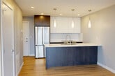 Located at 9922 111 Street in Edmonton's vibrant Oliver neighbourhood, this modern two-bedroom, two-bathroom unit offers a well-designed single-floor layout with contemporary finishes throughout. The open-concept kitchen is a standout feature, showcasing a large island with a quartz waterfall countertop, navy blue cabinetry, stainless steel appliances, crisp white upper cabinets, and elegant pendant lighting — ideal for both cooking and entertaining. Light hardwood flooring flows seamlessly through the living areas and bedrooms, enhancing the bright, airy atmosphere. Both bedrooms benefit from large floor-to-ceiling windows that frame sweeping views of the Edmonton downtown skyline, flooding the rooms with natural light. The primary bedroom includes a dedicated closet, while the second bedroom also features built-in closet storage. The two bathrooms are finished to a high standard, featuring marble-effect porcelain tile, undermount sinks with quartz countertops, dark wood vanity cabinetry, and chrome fixtures — one with a soaker tub and the other with a walk-in glass shower. A generously sized balcony with glass railings offers panoramic views of the Edmonton cityscape, providing an exceptional outdoor extension of the living space.