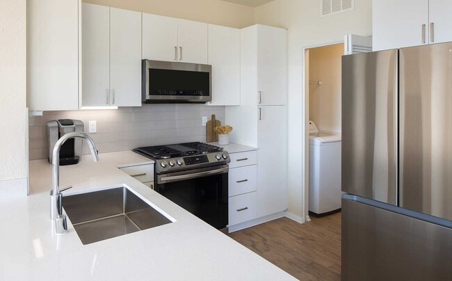Cocina renovada del Paquete II con gabinetes blancos, encimeras de cuarzo blanco, electrodomésticos de acero inoxidable y pisos de superficie dura. Lavandería dentro de la unidad con lavadora y secadora de tamaño estándar. - Avalon Simi Valley