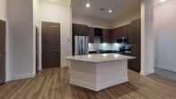 Located at 1300 Fourth Ave N in Nashville, Tennessee, this single-floor unit offers a well-designed, modern living space with quality finishes throughout. The open-concept kitchen serves as a central highlight, featuring rich dark cabinetry, a mosaic tile backsplash, stainless steel appliances including a French door refrigerator, built-in microwave, and range. A granite-topped kitchen island provides additional prep space and a natural gathering point, while wood-look flooring adds warmth and continuity across the main living area. A convenient coat hook station near the entry offers practical storage upon arrival. The bedroom is a calm, neutral retreat with plush carpeting and a window dressed with blinds that allow natural light to filter in, offering a view of the surrounding greenery. The bathroom is thoughtfully appointed with a granite-topped vanity, brushed nickel hardware, tile flooring, and a full tub-shower combination with white tile surround. Clean white walls and neutral tones throughout create a cohesive, move-in-ready aesthetic that is both functional and inviting for everyday living in the heart of Nashville.