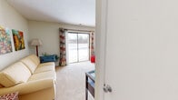 This one-bedroom, one-bathroom apartment at Woodbrook Apartments in Indianapolis, Indiana offers a thoughtfully organized layout across a single floor. The living area is bright and welcoming, featuring plush carpeting and a large sliding glass door that floods the space with natural light and provides direct access to an outdoor patio with exterior views. The living room flows seamlessly into a secondary seating area, offering flexible use of the space.

The dining room features warm hardwood-style flooring, a pendant light fixture overhead, and ample wall space, creating an inviting area for meals and entertaining. Adjacent to the dining room, the kitchen is equipped with oak cabinetry, granite-style countertops, and black appliances, including a range and dishwasher, all set over the same hardwood-style flooring.

The bathroom is finished with warm yellow walls, a wood vanity topped with a granite-style countertop, a large framed mirror, and hardwood-style flooring — offering a clean and functional design.

The bedroom provides a cozy retreat with soft carpeting, a window with outdoor views, and sufficient space for a full bedroom setup. Throughout the apartment, neutral wall tones create a cohesive, move-in-ready aesthetic well-suited for comfortable everyday living.