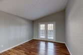 Located at 3415 Havenbrook Dr in Houston, TX, this well-appointed single-story unit offers a thoughtful layout across a comfortable footprint. Rich hardwood-style flooring runs throughout the space, lending warmth and continuity to every room. The open-concept living and dining area is filled with natural light, highlighted by elegant French doors that open onto a private balcony — an ideal spot for outdoor relaxation. The kitchen is a standout feature, outfitted with dark espresso cabinetry, white quartz countertops, a center island with a built-in sink, and black appliances including a range and refrigerator. Recessed and overhead lighting ensures the space is well-lit throughout. The bedroom is a well-sized retreat, complete with a ceiling fan, a natural light-filled window with outdoor views, and direct access to a walk-in closet. The bathroom features a tiled tub-shower combination, dark cabinetry for storage, and wood-style flooring. Additional conveniences include a dedicated laundry area and a hallway connecting the key areas of the unit. Neutral gray walls and clean white trim complete the modern, move-in-ready aesthetic of this Houston residence.
