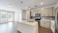 This well-appointed 2-bedroom, 2-bathroom single-story home features a thoughtfully designed open-concept layout that seamlessly connects the kitchen and living area. The kitchen is a standout, showcasing light wood-tone cabinetry, a decorative tile backsplash, a large center island with a white quartz countertop and undermount sink, and a full suite of stainless steel appliances including a refrigerator, range, and microwave. Pendant lighting with glass fixtures adds a modern touch overhead. Rich wood-look flooring runs throughout the main living areas, lending warmth and continuity to the space.

Both bedrooms are carpeted and feature ceiling fans, natural light from large windows, and generous walk-in closets equipped with wire shelving systems for practical storage. The primary bathroom is elegantly appointed with a dual-sink vanity featuring wood-grain cabinetry, quartz countertops, large-format tile flooring, a soaking tub, and a separate glass-enclosed shower. The second bathroom mirrors this refined aesthetic with similar finishes. A hallway connects the private areas of the home to the main living space, completing a functional and cohesive floor plan with a clean, contemporary ambiance throughout.