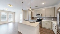 This well-appointed 2-bedroom, 2-bathroom single-story home features a thoughtfully designed open-concept layout that seamlessly connects the kitchen and living area. The kitchen is a standout, showcasing light wood-tone cabinetry, a decorative tile backsplash, a large center island with a white quartz countertop and undermount sink, and a full suite of stainless steel appliances including a refrigerator, range, and microwave. Pendant lighting with glass fixtures adds a modern touch overhead. Rich wood-look flooring runs throughout the main living areas, lending warmth and continuity to the space.

Both bedrooms are carpeted and feature ceiling fans, natural light from large windows, and generous walk-in closets equipped with wire shelving systems for practical storage. The primary bathroom is elegantly appointed with a dual-sink vanity featuring wood-grain cabinetry, quartz countertops, large-format tile flooring, a soaking tub, and a separate glass-enclosed shower. The second bathroom mirrors this refined aesthetic with similar finishes. A hallway connects the private areas of the home to the main living space, completing a functional and cohesive floor plan with a clean, contemporary ambiance throughout.