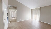 This single-floor residence features 2 bedrooms and 2 bathrooms within a well-organized layout that maximizes every square foot. The living room greets you with vaulted ceilings, light wood-style flooring, vertical blinds covering a sliding glass door, and a built-in shelving unit that adds both character and practical storage. It flows naturally into the dining area, creating an open, connected feel throughout the main living space.

The kitchen stands out with two-toned cabinetry — crisp white uppers paired with slate-blue lowers — complemented by light quartz countertops, a herringbone tile backsplash, stainless steel appliances including a dishwasher, and a peninsula for additional prep space. A pantry and dedicated laundry area add to the home's practicality.

The primary bedroom offers generous proportions with plush carpet, natural light from a window with blinds, and access to a spacious walk-in closet with dual built-in shelving systems. The second bedroom also features carpet flooring, a closet, and a bright window. Both bathrooms are clean and functional, each with a tiled tub-shower combo. One bathroom features a navy blue vanity that echoes the kitchen's design palette. With five total closets throughout, storage is abundant.