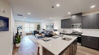 Located along Tamarack Circle in Skillman, NJ, this thoughtfully designed single-floor residence offers three bedrooms and two full bathrooms across a well-utilized open floor plan. The heart of the home is a stylish kitchen-living room combination, where dark shaker-style cabinetry, stainless steel appliances, a white quartz waterfall island with bar seating, and wood-look flooring create a modern yet inviting atmosphere. The kitchen flows seamlessly into the living area, which benefits from large windows offering views of the surrounding greenery and abundant natural light throughout. The spacious primary bedroom features plush carpeting and a generous window framing outdoor views, providing a peaceful retreat. Additional bedrooms are versatile, with closet storage and soft carpet underfoot, suitable for guests or a home office. The two bathrooms are finished with dark vanity cabinetry, white countertops, and clean tile work — one featuring a walk-in glass shower, and the other a full shower-tub combination. Recessed lighting throughout the residence enhances the bright, neutral palette, while consistent wood-look flooring in the main living areas ties the open-concept design together cohesively.