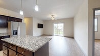 Located on Mortensen Road in Ames, Iowa, this well-appointed 3-bedroom, 3-bathroom residence offers a thoughtfully designed single-floor layout. The kitchen is a standout feature, showcasing rich dark cabinetry, granite countertops, stainless steel appliances including a refrigerator with ice maker, range, microwave, and dishwasher, complemented by light wood-style flooring and elegant pendant lighting over a central island. The open living area flows seamlessly from the kitchen, with light hardwood-style flooring, a ceiling fan, and sliding glass doors that open to a private balcony with outdoor views. Each of the three bedrooms features plush carpeting, ceiling fans, and windows that allow natural light to filter in. Each bedroom also includes its own closet for ample storage. The three bathrooms are finished consistently with wood-look tile flooring, dark-framed vanity mirrors, granite-topped vanities with dark cabinetry, and bathtub-shower combinations. The neutral color palette throughout creates a clean, modern ambiance, while the cohesive finishes across every room give the home a polished and unified aesthetic.
