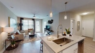 This single-floor, two-bedroom, two-bathroom residence offers a thoughtfully designed open-concept layout that seamlessly connects the kitchen, dining, and living areas. The kitchen is a functional centerpiece, featuring white shaker cabinetry, quartz countertops, stainless steel appliances, a dedicated pantry, and a spacious island with pendant lighting and bar seating. Wood-style flooring flows throughout the common areas, enhancing the cohesive, contemporary aesthetic.

The living room is bright and inviting, benefiting from large windows and a glass-panel door that draw in natural light and provide outdoor views. A ceiling fan adds comfort, while the neutral color palette creates a warm, relaxed atmosphere.

Each bedroom features a distinctive warm-toned accent wall, ceiling fans, large windows with outdoor views, and direct access to walk-in closet space. The primary bathroom includes a glass-enclosed shower, white vanity cabinetry with quartz countertops, and framed mirrors. The second bathroom echoes this clean, modern design with open shelving and direct bedroom access, offering added convenience for residents.
