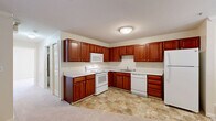 This one-bedroom, one-bathroom residence in Allison Park, Pennsylvania offers a practical and comfortable single-floor layout. The kitchen is a standout feature, showcasing rich cherry wood cabinetry with brass hardware, white appliances including a range, over-the-range microwave, dishwasher, and refrigerator, along with light-toned countertops and easy-care tile flooring. The L-shaped kitchen layout maximizes counter and storage space efficiently.

The generously sized primary bedroom is carpeted and features two large double-door closets, providing ample storage. It connects conveniently to an additional room, visible through a doorway, which offers supplementary shelving and storage. A window in the bedroom area allows natural light to brighten the soft, neutral-toned space.

The bathroom includes a full-size soaking tub and shower combination with a clean white surround, complemented by tile flooring that mirrors the kitchen. A dedicated utility room rounds out the functional layout of this residence.

Throughout the home, neutral wall tones and carpet flooring in the living areas create a calm, move-in-ready ambiance. The efficient floor plan makes excellent use of the available space, offering all essential living areas in a well-organized, single-level arrangement.