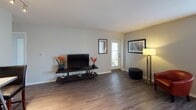 This single-floor residence at 1217 E Prairie Brook Dr in Palatine, Illinois offers a well-designed layout that balances comfort and functionality. The living area is a welcoming space highlighted by rich, dark hardwood-style flooring, neutral walls, and natural light streaming in through a glass door that leads to the exterior. The open, airy feel of this room provides a versatile setting for relaxing or entertaining.

The kitchen is thoughtfully outfitted with crisp white cabinetry, light countertops, and a full suite of stainless steel appliances, including a refrigerator, range, and over-the-range microwave. The hardwood-style flooring continues here, tying the space together seamlessly.

The bedroom is a serene retreat featuring soft carpeting, neutral tones, and a window that allows natural light to filter in. A closet with bi-fold doors provides ample storage, and the room's understated design creates a calm, restful atmosphere.

The bathroom is finished in a clean, contemporary style with white tilework, a large vanity mirror, bright overhead lighting, and a tub-shower combination. Chrome fixtures and white surfaces contribute to a crisp, polished look throughout.

The overall layout, as viewed from above, reveals an efficient and cohesive floor plan where each room flows naturally into the next, making this residence a comfortable and practical home in the Palatine community.