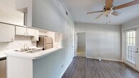 This one-bedroom, one-bathroom unit in Lafayette, Louisiana offers a functional and well-appointed layout across a single floor. The galley-style kitchen is efficiently designed with ample grey cabinetry, white quartz-style countertops, a tiled backsplash, stainless steel appliances including a refrigerator, electric range, and microwave, and durable wood-look flooring. A peninsula counter opens the kitchen toward the adjacent dining and living area, enhancing the sense of connectivity throughout. The dining area features light hardwood-style flooring, a classic multi-bulb chandelier, and a window with blinds that brings in natural light. A ceiling fan in the living space adds comfort and airflow. The bedroom is comfortably sized, outfitted with soft carpeting, crown molding, a textured ceiling, and a window with blinds providing natural light. It offers direct access to both the dedicated closet and the full bathroom. The bathroom includes a full tub and shower combo with white tile surround and chrome fixtures. Throughout the unit, neutral grey walls, white trim, and crown molding create a clean, cohesive aesthetic suited for comfortable everyday living.
