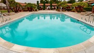 Located at 3340 Topaz Lane in Fullerton, California, this two-story property is nestled within a thoughtfully maintained community that blends comfort with resort-style living. The exterior grounds make a strong first impression, showcasing lush, drought-tolerant landscaping complete with towering palm trees, columnar cypress, ornamental boulders, and vibrant tropical plantings set against a backdrop of wood-chip mulched beds — all framed by gated access for added privacy and security. The community's outdoor amenities are a true highlight. A generously sized swimming pool with vivid turquoise water serves as the centerpiece of the recreational area, surrounded by a clean concrete deck ideal for lounging. Adjacent to the pool, a bubbling spa with stainless steel entry rails offers a relaxing retreat. The overall outdoor environment carries a warm, California-resort ambiance, enhanced by the terra cotta tile rooflines visible throughout the community. The combination of mature, curated landscaping and well-kept shared amenities reflects a community that prioritizes both aesthetics and functionality, making this Fullerton address an inviting place to call home.