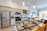 This well-appointed one-bedroom, one-bathroom residence in Salem, Massachusetts offers a thoughtfully designed open-concept layout with soaring ceilings that lend an airy, expansive feel throughout. The kitchen is a standout feature, showcasing sleek taupe cabinetry, a white subway tile backsplash, dark stone countertops, stainless steel appliances, and a large central island with pendant lighting — ideal for both cooking and casual dining. Light wood-tone flooring flows seamlessly from the kitchen into the living area, where oversized windows invite an abundance of natural light and frame views of the surrounding neighborhood. The living room provides a welcoming, versatile space with clean lines and a neutral palette. The bedroom is generously proportioned, featuring large windows with outdoor views, direct access to a walk-in closet, and warm hardwood-style flooring. The full bathroom is finished with marble-style tile flooring, a single vanity with stone countertop, built-in shelving, and a full soaking tub with shower. Additional highlights include three closets for ample storage and a dedicated in-unit laundry area, making this residence as functional as it is refined.
