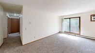 This 2-bedroom, 1-bathroom unit in Sioux Falls, SD, offers a well-organized single-floor layout designed for comfortable everyday living. The living area is bright and open, featuring plush carpeting, neutral white walls, and a sliding glass door that floods the space with natural light and provides access to an outdoor balcony area with views of surrounding greenery. A textured ceiling and baseboard heating are consistent throughout the unit.

The primary bedroom is generously sized and includes a ceiling fan with light fixture, a window overlooking the outdoors, baseboard heating, and soft carpeting. The second bedroom mirrors a similar aesthetic with carpeting, a window for natural light, and a clean, neutral finish. Both bedrooms offer ample space for furnishings.

A hallway connects the bedrooms to the full bathroom, which features tile flooring, a tub/shower combo, a toilet, and warm wood-toned cabinetry with overhead storage. A sliding wood-panel closet provides dedicated storage in the bedroom area, adding to the unit's overall practicality.

Throughout the unit, wood-trimmed doors and windows, textured ceilings, and consistent neutral tones create a cohesive and functional atmosphere suited for a variety of lifestyles.
