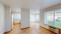 Located at 5417 W Shawnee Ave in Spokane, WA, this one-bedroom, two-bathroom unit offers a well-organized, single-floor layout designed for comfortable everyday living. The open-concept living and kitchen area is bright and welcoming, with light hardwood flooring running throughout the main living spaces and textured ceilings that add a subtle visual detail. Multiple windows dressed with horizontal blinds allow natural light to flow freely, creating an airy atmosphere throughout.

The kitchen is efficiently laid out with warm oak cabinetry, tile backsplash, white appliances including a refrigerator, electric range, and over-the-range microwave, and a raised breakfast bar that separates it from the living area. A notable feature of the living room is a striking bay window that frames outdoor views and floods the space with additional natural light.

The bedroom features plush carpeting, a window with blinds, and baseboard heating, offering a quiet and comfortable retreat. Both bathrooms are outfitted with hardwood-style flooring, oak vanities, and accessibility grab bars, with one bathroom featuring a full tub/shower combination. A utility area with an electrical panel provides added practicality. Baseboard heating is present throughout the unit, ensuring consistent warmth year-round.