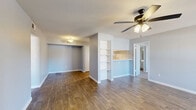 Located at Windmill Lakes Blvd in Houston, TX, this 2-bedroom, 2-bathroom residence offers a well-organized single-floor layout designed for comfortable everyday living. The open-concept living and kitchen area serves as the heart of the home, featuring warm wood-look hardwood flooring throughout. The living room is highlighted by a classic fireplace, a ceiling fan with light fixture, and a sliding glass door that fills the space with natural light and leads out to a private balcony. The balcony features a wood-paneled railing and overlooks a tree-lined outdoor setting, providing a relaxing retreat. A built-in shelving unit elegantly divides the living area from the kitchen pass-through, adding both function and character. The kitchen is equipped with white cabinetry, a subway tile backsplash, white countertops, black appliances including a refrigerator and dishwasher, and a stainless steel sink. Both bedrooms are carpeted and include ceiling fans, closets, and a calm, neutral color palette. The two full bathrooms each feature a tub-shower combination with white surround paneling, wood-look flooring, and white vanities. Additional spaces include a laundry area, a pantry, a hallway, and three closets for ample storage throughout.