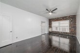 Located at 854 S Oxford Ave, this single-floor unit offers a well-organized layout comprising a bedroom, kitchen, closet, bathroom, and entrance. The spacious bedroom is a standout feature, showcasing rich, dark hardwood floors that run throughout the main living areas, a textured ceiling with a ceiling fan, and a striking exposed brick accent wall framing a large window that fills the room with natural light. Two doors from the bedroom provide access to the closet and other areas of the unit, adding to the functionality of the space. The closet is generously sized, equipped with built-in hanging rods for ample storage. The kitchen contrasts beautifully with the rest of the unit, featuring gleaming marble-style porcelain tile floors, crisp white cabinetry, a stainless steel refrigerator, a gas range, a tile backsplash, and a single-basin sink — all combining to create a clean, functional cooking space. The bathroom continues the tile flooring theme with classic white hexagonal mosaic tiles, complemented by clean white walls and fixtures. The entrance corridor connects all areas of the unit cohesively, maintaining the dark hardwood flooring and a bright, neutral color palette throughout.