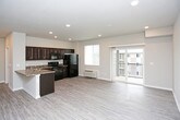 This single-floor residence offers a thoughtfully designed open-concept layout that connects the living, dining, and kitchen areas into one cohesive and functional space. Light-toned luxury vinyl plank flooring runs throughout the main living areas, complementing the neutral wall tones and recessed lighting that keep the space feeling bright and airy.

The living area is generously sized and features a sliding glass door that opens to a private balcony, allowing natural light to fill the room and providing outdoor views. The kitchen is well-equipped with rich dark espresso cabinetry, granite-style countertops, and a full suite of black appliances including an electric range, microwave, dishwasher, and refrigerator. A double-basin sink and ample cabinet storage add to the kitchen's practicality. A dedicated in-unit laundry area with a washer and dryer is conveniently accessible directly from the kitchen.

The bedroom is finished with plush wall-to-wall carpeting, a ceiling fan with light fixture, a wall-mounted HVAC unit, and a window that brings in natural light. The bathroom features dark wood cabinetry paired with granite-style countertops, a large vanity mirror, and overhead lighting, offering a clean and functional design. Throughout the residence, white trim and baseboards provide a polished, cohesive aesthetic.