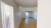 Located at 4140 W McDowell Rd in Phoenix, Arizona, this single-floor unit offers a straightforward and functional layout designed for comfortable everyday living. The main living area immediately impresses with its vaulted ceilings that rise dramatically, creating a sense of openness and volume. Large vertical-blind-covered sliding doors allow natural light to pour in, brightening the space and offering outdoor access. Light tan ceramic tile flooring extends throughout the living and kitchen areas, providing a clean and cohesive look that is easy to maintain in the Arizona climate. The galley-style kitchen is efficiently arranged, featuring warm wood cabinetry on both sides, light countertops, a double-basin sink, and white appliances including a coil-top range and refrigerator — making the most of the available space. The bedroom is carpeted in neutral tones, offering a softer, quieter environment, and features a textured ceiling consistent with the rest of the unit. The bathroom is tiled in matching flooring and includes a full tub and shower combination, toilet, and vanity with wood cabinetry below. Throughout the unit, white walls and textured ceilings maintain a clean, neutral palette that is ready for personalization.