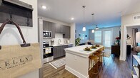 Located at 2002 Wilson Ave in Panama City, FL, this thoughtfully designed one-bedroom, one-bathroom residence offers a comfortable and efficient single-floor layout. The open-concept living, dining, and kitchen area serves as the heart of the home, anchored by warm wood-look flooring and neutral tones throughout. The kitchen is a standout feature, equipped with stainless steel appliances including a French door refrigerator, electric range, built-in microwave, and dishwasher. Dark wood-grain cabinetry with sleek hardware reaches to the ceiling, complemented by a white subway tile backsplash and crisp quartz countertops. A large kitchen island with bar seating and pendant lighting above creates an ideal space for dining and entertaining. The living room benefits from natural light through large windows and a patio door, with a ceiling fan adding comfort. The bedroom is a serene retreat with ample natural light, a ceiling fan, and a dedicated closet. The bathroom features a modern vanity with quartz countertop, wood-grain cabinetry, and wood-look flooring. A dedicated in-unit laundry room houses a full-size washer and dryer with overhead shelving. The space also includes a private patio, completing this well-appointed residence.