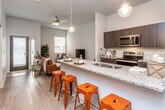 This single-floor residence offers a thoughtfully designed open-concept layout that seamlessly connects the kitchen, dining, and living areas. The kitchen is a standout feature, equipped with stainless steel appliances including an electric range, microwave, and refrigerator, complemented by dark espresso cabinetry, a white tile backsplash, and granite countertops. A generously sized granite-topped island with bar seating serves as both a functional workspace and a casual dining hub, illuminated by pendant lighting overhead. Light wood-style flooring runs throughout the main living areas, adding warmth to the neutral color palette.

The living area is bright and welcoming, with a ceiling fan, natural light from multiple windows, and access to an exterior door. Both bedrooms are carpeted and feature tall ceilings, ceiling fans, and windows that bring in natural light, creating comfortable, restful retreats. The full bathroom includes a tub-shower combination, granite vanity with dark cabinetry, and wood-style flooring. A dedicated laundry area houses a full-size top-loading washer and dryer. The overall ambiance is modern and cohesive, with clean lines and contemporary finishes throughout.