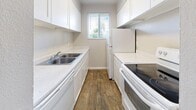 This single-floor, one-bedroom, one-bathroom residence offers a practical and comfortable layout across a compact yet efficiently organized footprint. Rich wood-look flooring flows throughout the main living areas and hallway, lending warmth and visual continuity to the space.

The living room serves as the heart of the home, featuring a classic corner fireplace with a dark surround that adds character and charm. A window with blinds allows natural light to brighten the room, while a wall-mounted HVAC unit provides climate control convenience.

The galley-style kitchen is thoughtfully designed, with white cabinetry lining both walls, light stone countertops, a double-basin stainless steel sink, a dishwasher, a refrigerator, and an electric range with cooktop. A centered window above the sink brings in natural light and adds an airy feel to the space.

A hallway connects the main living area to the private quarters, lined with crisp white doors and finished with the same wood-look flooring. The bedroom is generously proportioned, featuring plush carpeting and two sets of bifold closet doors that provide exceptional storage capacity.

The overall aesthetic is clean and neutral throughout, with white walls and trim creating a bright, move-in-ready atmosphere well-suited for comfortable everyday living.