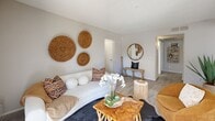 Located at 4748 W Sierra Vista Dr in Glendale, Arizona, this thoughtfully designed two-bedroom, four-bathroom residence offers a comfortable and cohesive single-floor layout. The living room serves as the heart of the home, featuring light wood-style flooring, a textured ceiling, and a sliding glass door that opens to a private outdoor balcony, allowing natural light to fill the space. Decorative woven wall accents and warm, earthy furnishings lend the living area a relaxed, bohemian character. A dedicated entrance and connecting hallway provide smooth flow throughout the unit, with wood-look flooring extending into the shared spaces. The hallway also reveals an in-unit stacked washer and dryer closet, adding everyday convenience. Each bedroom is carpeted for comfort, with windows that bring in natural light and views of the surrounding outdoor greenery. The primary bedroom offers a cozy, well-proportioned retreat, while the second bedroom is equally inviting. The four bathrooms are finished in clean white tones with wood-look flooring, tub-shower combinations, and bright vanities with ample counter space. Overall, the residence combines practical functionality with a warm, curated aesthetic in a compact and efficiently organized floor plan.