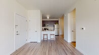 This well-appointed single-floor residence offers a thoughtfully designed open-concept layout that seamlessly connects the living and kitchen areas. The kitchen is a standout feature, outfitted with rich dark-toned cabinetry, granite countertops, and a full suite of stainless steel appliances including a refrigerator, range, and over-the-range microwave. A peninsula with bar-style seating for two creates a natural gathering point and provides additional prep space, making it equally functional and social. Warm hardwood-style flooring flows consistently throughout the main living areas, contributing to a cohesive and inviting aesthetic. The living space is open and airy, with clean white walls and ample room to arrange furnishings comfortably. The bedroom benefits from generous natural light through a large window with blinds, filling the room with brightness and warmth. The bathroom features light tile flooring, a dark-toned vanity with a single sink, a large mirror, and clean white walls that keep the space feeling fresh and functional. The overall design balances modern finishes with a neutral palette, creating a versatile and welcoming environment throughout.