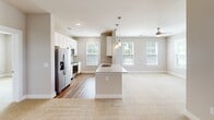 This well-appointed 2-bedroom, 2-bathroom single-floor residence in Charlotte, NC offers a thoughtfully designed open-concept layout. The kitchen serves as the heart of the home, anchored by a large center island with granite countertops, an undermount sink, and pendant lighting overhead. White cabinetry and stainless steel appliances, including a refrigerator and range, complete the space, which flows seamlessly into the carpeted living area brightened by multiple windows and a ceiling fan. A set of glass-paneled doors leads to an outdoor access point, filling the living space with natural light.

The primary bedroom is a comfortable retreat featuring plush carpet, a ceiling fan, and a window with exterior views. Its en-suite bathroom impresses with a dual-sink granite vanity, white cabinetry, a large mirror, and a separate walk-in shower. A spacious walk-in closet with wire shelving and hanging rods provides ample storage. The second bedroom mirrors the same warm, carpeted design with a ceiling fan and natural light. A second full bathroom offers a tub-shower combination and granite vanity. A dedicated in-unit laundry room with side-by-side washer and dryer on wood-look flooring adds everyday convenience throughout this clean, modern home.