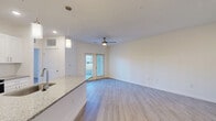 Located at 100 Plyer Cir in Indian Trail, NC, this thoughtfully designed one-bedroom, one-bathroom residence offers a clean, modern aesthetic across its single-floor layout. Light-toned hardwood-style flooring runs throughout, lending a cohesive and airy feel to every room.

The heart of the home is an open-concept living, dining, and kitchen area. The kitchen is appointed with crisp white shaker cabinetry, granite countertops, stainless steel appliances including a refrigerator, range, microwave, and dishwasher, and a peninsula with pendant lighting that doubles as a breakfast bar. Recessed lighting and a built-in wine rack add refined touches.

The living area is bright and welcoming, featuring a ceiling fan, neutral walls, and French doors that open to the outdoors, filling the space with natural light and exterior views. The bedroom is a comfortable retreat, complete with its own ceiling fan, a large window overlooking the surrounding community, and ample closet space — three closets are included throughout the unit.

The bathroom continues the home's design language with a granite-topped white vanity and clean finishes. A dedicated laundry area and utility room add practical convenience. Overall, the space presents a fresh, modern living environment well-suited to everyday comfort.