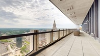 Located at 17 Asylum Street in the heart of Hartford, Connecticut, this expansive high-rise terrace occupies an elevated position that delivers some of the most commanding views in the city. The terrace stretches along the building's exterior as a long, open-air corridor defined by large-format light stone tiling underfoot and a covered overhead structure with recessed ceiling panels that provide partial shelter from the elements.

A continuous railing system composed of dark metal framing interspersed with textured concrete pillars lines the outer edge of the terrace, providing safety while preserving unobstructed sightlines. The views extend across the Hartford cityscape, with the historic Travelers Tower — one of Connecticut's most recognized landmarks — prominently visible, along with the Connecticut River winding through the landscape beyond the downtown skyline, and expansive greenery stretching to the horizon.

On the interior side, floor-to-ceiling glass curtain walls with vertical metal columns allow abundant natural light to flow in and maintain a strong visual connection between the terrace and the building's interior. Casual outdoor seating is positioned along the terrace, creating a functional space suitable for relaxation or gatherings. This terrace offers a rare and impressive elevated outdoor experience in the heart of downtown Hartford.