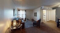Located at 6161 E Grant Rd in Tucson, Arizona, this single-floor residence offers a practical and cohesive layout designed for comfortable everyday living. The living room serves as the heart of the home, featuring plush carpeting, a textured ceiling, and a front-facing window dressed with blinds and curtain panels that allow natural light to filter in. The space flows naturally into a dedicated dining area, which is distinguished by a bold charcoal accent wall, hardwood-style flooring, and a ceiling fan overhead — a practical touch well-suited to the Arizona climate. The kitchen is efficiently designed, offering warm wood cabinetry, a stainless steel sink, laminate countertops, white appliances including a refrigerator and range, and a window fitted with plantation shutters that brightens the space. The bedroom is a serene retreat, carpeted for comfort, with a textured ceiling, windows with blinds and sheer curtains, and access to a walk-in closet. The bathroom features a wide vanity with ample cabinet storage, a large mirror, and hardwood-style flooring, providing a clean and functional finish. Throughout the residence, a consistent blend of carpet and wood-style flooring ties the spaces together cohesively.