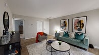 Located at 1491 Druid Valley in Atlanta, GA, this one-bedroom, one-bathroom model unit showcases a thoughtfully designed single-floor layout spanning approximately 800 square feet. The open-concept living room features warm wood-look flooring, neutral gray walls, and abundant natural light streaming through large French doors that lead to a private balcony overlooking tree-lined surroundings — a serene outdoor retreat ideal for relaxing. The living area offers generous space for comfortable seating arrangements and flows naturally into the dining area, which is highlighted by a modern pendant light fixture and a window framing views of the lush exterior. The kitchen is outfitted with white shaker cabinetry, dark countertops, a classic subway tile backsplash, and stainless steel appliances, including a gas range, dishwasher, and full-size refrigerator. The bedroom features plush carpeting, a window with decorative curtains, and ample room for a full furniture suite. The bathroom is clean and functional, featuring a tub/shower combo with tile surround, a vanity with dark countertop, and wood-look flooring. Throughout the unit, a cohesive, contemporary aesthetic ties each space together with stylish, modern touches.