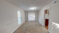 This single-floor, 3-bedroom, 2-bathroom home in Essex offers a practical and comfortable layout designed for everyday living. The spacious living area features plush wall-to-wall carpeting, a textured ceiling, and multiple windows with blinds that allow generous natural light to filter in. Sliding glass doors provide access to the outdoors, enhancing the open feel of the main living space.

Each of the three bedrooms is carpeted and equipped with a ceiling fan and light fixture. The bedrooms feature ample closet space, including both walk-in and standard closets, and neutral-toned walls that create a calm, versatile atmosphere.

The kitchen is outfitted with warm wood cabinetry, dark granite-style countertops, a stainless steel sink, a dishwasher, and a refrigerator, all complemented by wood-look flooring that adds warmth and durability.

The two bathrooms are clean and functional. One features a vanity with rich wood cabinetry and granite-style countertops paired with a tub-shower combo, while the second offers a straightforward tub-shower combination with brushed nickel fixtures. Both bathrooms include wood-look flooring for a cohesive aesthetic throughout the home.