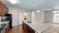 Located at 10449 Atlee Station Road in Mechanicsville, VA, this two-bedroom, two-bathroom residence offers a well-designed single-floor layout with a thoughtful mix of finishes and functional spaces. The kitchen serves as the centerpiece of the home, showcasing rich cherry wood cabinetry, granite countertops, and a large island with a double stainless steel sink and elegant pendant lighting overhead. Black appliances, including a range, built-in microwave, and refrigerator, complete the kitchen's cohesive design. Hardwood-style flooring runs through the kitchen and main living areas, adding warmth and durability. Both bedrooms feature soft carpeting and neutral wall tones, with the primary bedroom offering a ceiling fan and direct access to its en-suite bathroom. Each bedroom benefits from natural light through windows with blinds. The two bathrooms are finished with stone-tile flooring and cherry wood vanities topped with granite, maintaining a consistent design language throughout. One bathroom includes a soaking tub alongside a shower-tub combo. Two closets provide practical storage. The overall ambiance is clean, neutral, and move-in ready, making it a comfortable and well-appointed residence in a convenient Mechanicsville location.