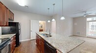 Located at 10449 Atlee Station Road in Mechanicsville, VA, this two-bedroom, two-bathroom residence offers a well-designed single-floor layout with a thoughtful mix of finishes and functional spaces. The kitchen serves as the centerpiece of the home, showcasing rich cherry wood cabinetry, granite countertops, and a large island with a double stainless steel sink and elegant pendant lighting overhead. Black appliances, including a range, built-in microwave, and refrigerator, complete the kitchen's cohesive design. Hardwood-style flooring runs through the kitchen and main living areas, adding warmth and durability. Both bedrooms feature soft carpeting and neutral wall tones, with the primary bedroom offering a ceiling fan and direct access to its en-suite bathroom. Each bedroom benefits from natural light through windows with blinds. The two bathrooms are finished with stone-tile flooring and cherry wood vanities topped with granite, maintaining a consistent design language throughout. One bathroom includes a soaking tub alongside a shower-tub combo. Two closets provide practical storage. The overall ambiance is clean, neutral, and move-in ready, making it a comfortable and well-appointed residence in a convenient Mechanicsville location.