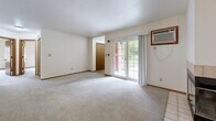 Located on Green Rd in Pewaukee, Wisconsin, this single-floor, two-bedroom, one-bathroom home offers a functional and comfortable layout. The open living room is a standout space, anchored by a tile-surround fireplace with glass doors and a ceiling fan overhead. Sliding glass doors flood the room with natural light and provide views of the lush outdoor greenery beyond. The kitchen is equipped with warm oak cabinetry, dark laminate countertops, tile flooring, and white appliances including a refrigerator, range, and dishwasher. A pass-through countertop connects the kitchen to the living area, enhancing the open feel of the shared space. The generously sized primary bedroom features plush carpet, a large window for natural light, and a full-width sliding closet. The second bedroom is equally well-appointed with soft carpeting and warm-toned wood doors and trim throughout. The full bathroom includes a tub-shower combination with clean white surround and tile flooring. A dedicated laundry room with wire shelving, washer and dryer, and tile floors adds everyday convenience. Neutral tones and consistent wood trim details lend the home a cohesive, move-in-ready aesthetic.