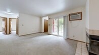 Located on Green Rd in Pewaukee, Wisconsin, this single-floor, two-bedroom, one-bathroom home offers a functional and comfortable layout. The open living room is a standout space, anchored by a tile-surround fireplace with glass doors and a ceiling fan overhead. Sliding glass doors flood the room with natural light and provide views of the lush outdoor greenery beyond. The kitchen is equipped with warm oak cabinetry, dark laminate countertops, tile flooring, and white appliances including a refrigerator, range, and dishwasher. A pass-through countertop connects the kitchen to the living area, enhancing the open feel of the shared space. The generously sized primary bedroom features plush carpet, a large window for natural light, and a full-width sliding closet. The second bedroom is equally well-appointed with soft carpeting and warm-toned wood doors and trim throughout. The full bathroom includes a tub-shower combination with clean white surround and tile flooring. A dedicated laundry room with wire shelving, washer and dryer, and tile floors adds everyday convenience. Neutral tones and consistent wood trim details lend the home a cohesive, move-in-ready aesthetic.