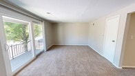 Located at 69 West Summerset Lane, this single-story home spans 820 square feet and features 3 bedrooms, 1 bathroom, a living room, and a hallway connecting the layout. The living room features a mix of warm hardwood-style flooring near the entryway and carpet, with neutral-toned walls and a front entry door that leads directly into the space. The kitchen, visible in the dollhouse view, includes wood-toned cabinetry and a functional countertop workspace. All three bedrooms are carpeted with neutral beige walls, providing a clean and versatile canvas. The primary bedroom measures 150 square feet and, like the secondary bedrooms, benefits from windows overlooking lush, tree-lined outdoor views, allowing natural light to fill the rooms. Several bedrooms feature decorative chair-rail molding along the walls, adding a subtle architectural detail. The shared bathroom includes a full-size soaking tub with an overhead shower and white tile surround. Throughout the home, consistent neutral tones, carpet flooring, and white trim create a cohesive and understated aesthetic. A central hallway connects the bedrooms and bathroom for a practical and efficient floor plan.