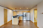 Located at 314 N Franklin St in downtown Madison, WI, this one-bedroom, two-bathroom unit offers a well-designed layout that maximizes every square foot. The open-concept kitchen and living area serves as the heart of the space, featuring light maple cabinetry, dark granite-style countertops, a peninsula with pendant lighting, and a full suite of stainless steel appliances including a refrigerator, electric range, microwave, and dishwasher. Recessed lighting and warm-toned hardwood-style flooring create a bright, inviting atmosphere in the main living area. Large windows with views of the surrounding neighborhood allow natural light to fill the space throughout the day. The bedroom is a quiet, carpeted retreat with a double-door closet and a dedicated window that brings in additional natural light. Two bathrooms serve the unit, each finished with maple vanities, dark countertops, and tile flooring, maintaining a consistent design language with the rest of the space. A hallway connects the rooms efficiently, contributing to a clean and functional flow. The unit's compact yet thoughtfully organized footprint makes it a practical option for urban living in the heart of Madison.