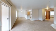 Located at 4525 S Warner St in Tacoma, Washington, Unit G68 is a single-floor residential unit offering a practical and comfortable layout. The open-concept living and dining area is finished with neutral wall-to-wall carpeting and features a ceiling fan with light fixture, a baseboard heating system, and a sliding glass door that leads to an outdoor patio, allowing natural light to fill the space. Wall-mounted sconce lighting adds a warm accent throughout the living area.

The kitchen is efficiently designed with white cabinetry, light-toned laminate countertops, a white electric coil range with overhead ventilation, and patterned vinyl tile flooring. A set of natural wood-toned bi-fold doors provides access to a pantry or storage closet, maximizing utility within the kitchen space.

The unit includes multiple bedrooms, each carpeted and featuring baseboard heaters and windows with blinds that bring in natural light and outdoor views of surrounding greenery. One bedroom includes access to a dedicated walk-in closet with built-in hanging rods, offering ample storage. The bedrooms are well-proportioned and versatile in their use. Overall, the unit presents a clean, neutral palette throughout, making it a functional and move-in ready residential space in Tacoma.