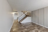 Located at 10025 E Girard Ave in Denver, CO, this two-story home offers a functional and comfortable layout spread across two floors. The main level features an open living room with durable wood-look plank flooring, neutral gray walls, and a textured ceiling, creating a clean and modern aesthetic. A staircase with sleek iron railings connects the two levels, serving as a subtle architectural focal point. The kitchen is well-equipped with white shaker-style cabinetry, light marble-look countertops, and black appliances including a gas range, dishwasher, and refrigerator, all complemented by wood-look flooring and a skylight-style overhead fixture that brightens the space. The full bathroom features a tub-shower combination with a crisp white surround, a toilet, and a vanity, finished in a clean, neutral palette. Upstairs, both bedrooms are carpeted for added comfort and each include sliding-door closets. The generously sized primary bedroom offers ample space for furnishings. A hallway connects the upper-level rooms, completing the practical layout. Throughout, consistent neutral tones and updated finishes give the home a cohesive, move-in-ready feel.