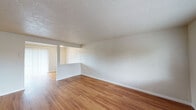 Located at 3105 Gateway St in Springfield, Oregon, this single-floor unit offers a clean, functional layout with a cohesive design throughout. The living area is bright and open, featuring warm hardwood-style flooring that flows through the main living spaces, white walls, and a textured ceiling that adds subtle character. Natural light enters through a large front-facing window, creating an inviting atmosphere. The layout connects the living area to a dining space and kitchen in a practical, open flow. The kitchen is well-appointed with white shaker-style cabinetry, dark countertops, a stainless steel electric range with overhead ventilation, and a stainless steel refrigerator — offering both style and functionality. The bathroom features a white vanity with dark countertops and a framed mirror, consistent with the updated finishes seen throughout the unit. The bedroom is carpeted for added comfort and includes a window that brings in natural light. Vertical blinds on a sliding door provide access to an outdoor area, allowing additional natural light into the interior. Overall, the space presents a clean, updated aesthetic with consistent finishes, making it a practical and comfortable single-level home in Springfield.