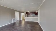 Located at 8334 David Dr in Woodridge, Illinois, this single-floor residence offers a thoughtfully designed layout with modern finishes throughout. The open-concept living area is anchored by rich, dark hardwood-style flooring and neutral gray walls, creating a clean and contemporary ambiance. A sliding glass door floods the living space with natural light while providing access to the outdoors.

The kitchen is a standout feature, boasting dark espresso cabinetry with sleek hardware, crisp white quartz countertops, and a striking blue mosaic tile backsplash. Stainless steel appliances — including a refrigerator, range, microwave, and dishwasher — complete this functional and stylish culinary space. A peninsula counter connects the kitchen to the living area, making it ideal for casual dining or entertaining.

The bedrooms are finished with plush carpet and neutral gray walls, offering a comfortable retreat. Each room includes closet storage, and natural light filters in through windows with blinds. The bathroom features a full soaking tub with a shower, white tile surround, and a decorative blue mosaic accent border that ties cohesively to the kitchen's design palette. Textured ceilings are present throughout the residence.