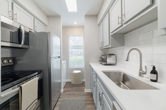 Cocina con encimeras de cuarzo y electrodomésticos de acero inoxidable. - Oakgate at Pecan Grove