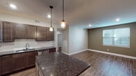 Located at 619 Clancy Ave NE in Grand Rapids, Michigan, this single-floor space offers a thoughtfully designed interior with modern finishes throughout. The kitchen serves as a central highlight, featuring rich dark-stained cabinetry, dark granite countertops, and a classic white subway tile backsplash. A center island with a granite surface and pendant lighting above provides additional workspace and a natural gathering point. Stainless steel appliances, including a refrigerator, range, built-in microwave, and dishwasher, complete the well-equipped kitchen setup.

The open-concept layout connects the kitchen to a generously sized living area, finished with durable hardwood-style flooring that flows consistently throughout the main living spaces. Neutral-toned walls in warm beige and taupe tones contribute to a calm, cohesive atmosphere, while windows allow natural light to brighten the space.

The bathrooms maintain the same design language, with dark wood vanities, white countertops, and neutral tile flooring in the full bath, which also includes a soaking tub. A half bath features a matching vanity and clean, simple finishes. The overall ambiance is modern, clean, and move-in ready.